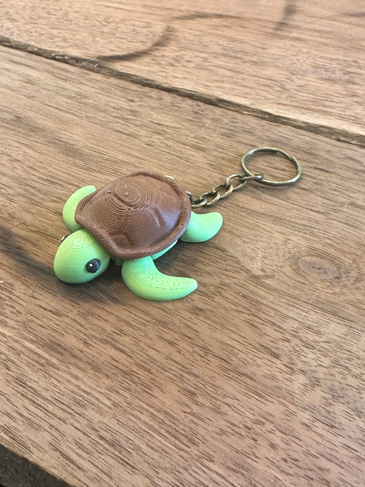Green turtle keychain with brown shell on a wooden surface