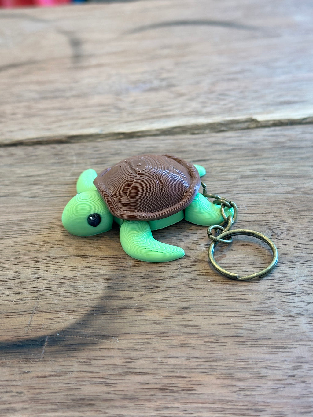 Green turtle keychain with brown shell on a wooden surface