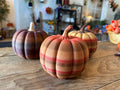 Three large 3D printed pumpkins in multicolor rustic fall finishes displayed on a wooden table at AO3D.
