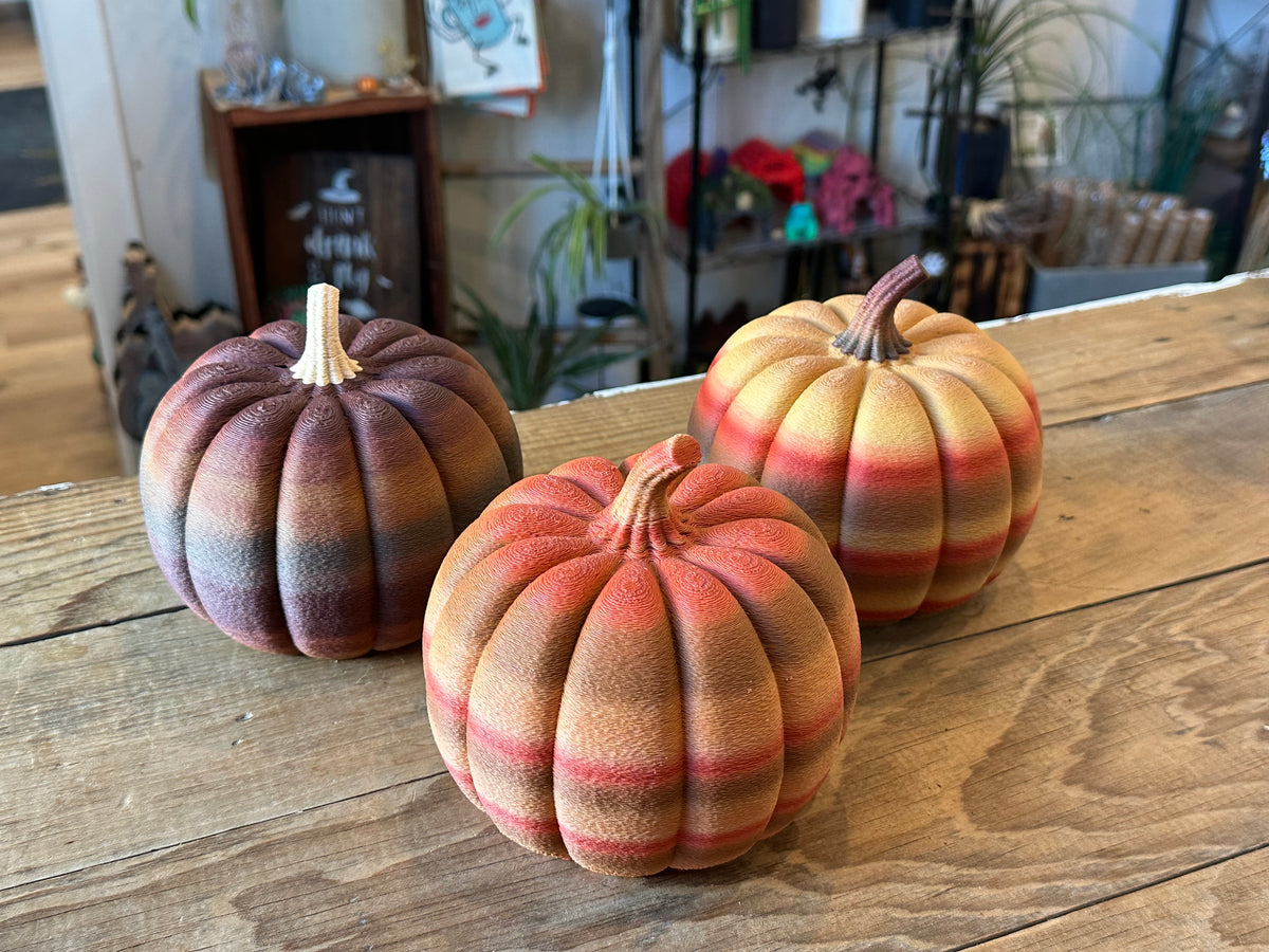 Three textured 3D printed decorative pumpkins in brown, orange, and yellow multicolor autumn finishes.