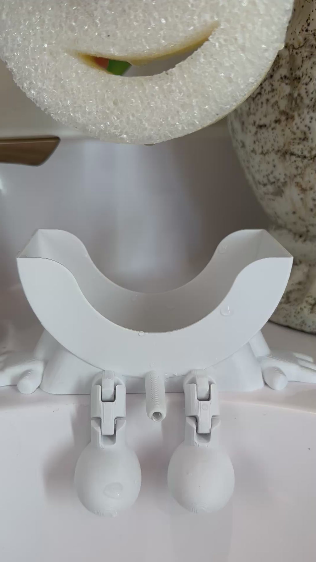 Close up video showing Little Dripper sponge holder draining water in bathroom sink
